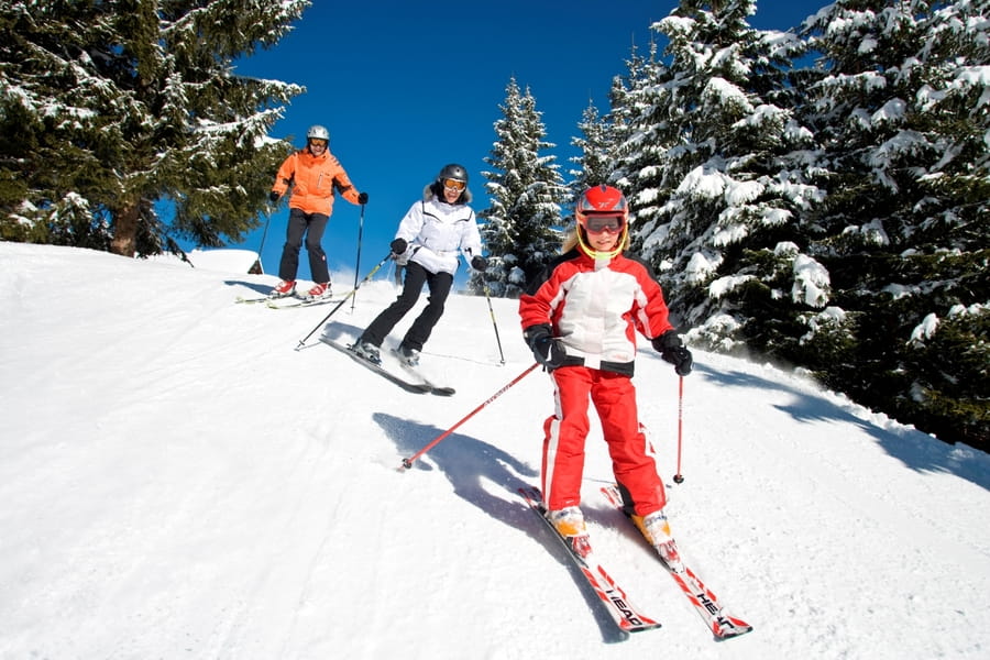 Drei Skifahrer fahren bei strahlendem Wetter und hervorragender Schneelage den Hang hinunter