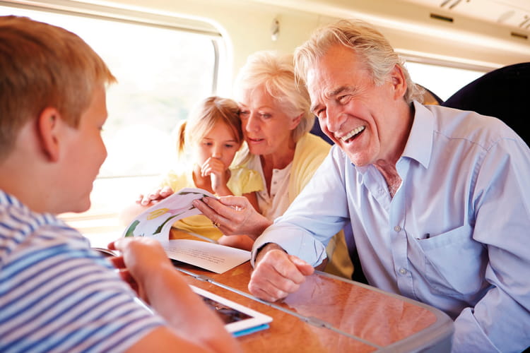 Ein älterer Mann und eine ältere Frau sitzen mit einem kleinen Mädchen und einem Jungen im Zug.
