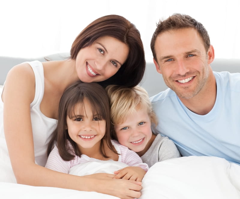 Vater, Mutter und zwei Kinder, ein Mädchen und ein Bub blicken in die Kamera