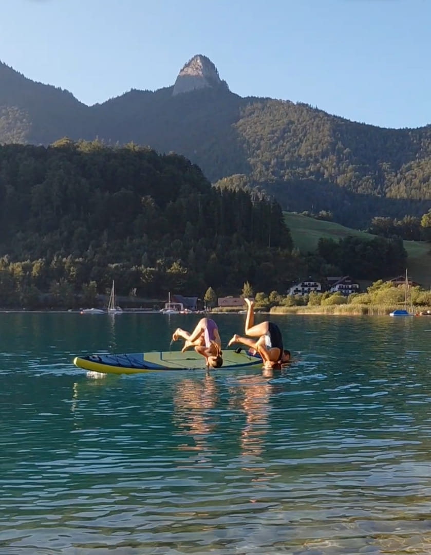 SUP Salto in der Abendsonne am Wolfgangsee mit Hintergrund Sommeraustein