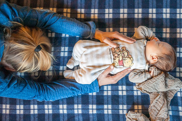 Frau beugt sich über Baby das am Boden liegt