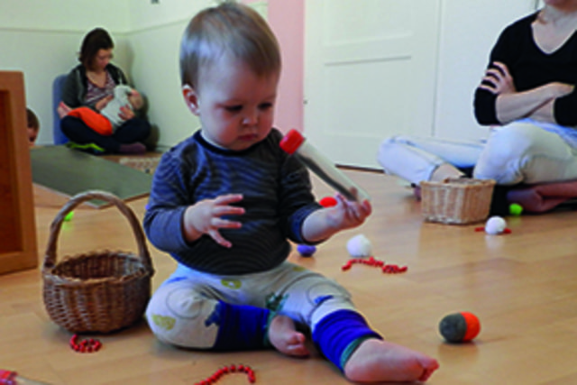 Kleinkind sitzend mit Spielzeug in der Hand